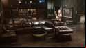 Vampire The Masquerade Swansong review: an official screenshot from Big Bad Wolf depicts a handsome if sterile apartment, the residence of a wealthy Boston banker; a lounge suite of glossy brown leather dominates the foreground, with bookshelves and abstract sculptures behind
