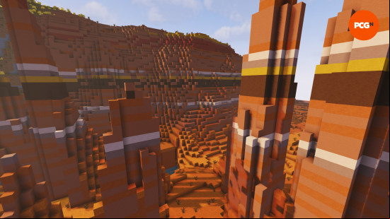 The sun illuminates the orange badlands Minecraft biome, with its red sand and yellow, brown, and orange terracotta.