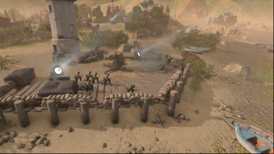 Tanks on a beach surrounded by sandbags firing artillery weapons