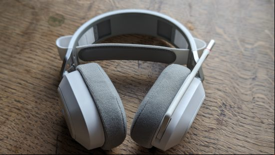 Corsair HS80 Max review: a white headset with retracted microphone appears on a wooden table.