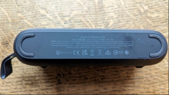 Anker Soundcore Motion 300 review: a black speaker with silver grille appears on a wooden surface.