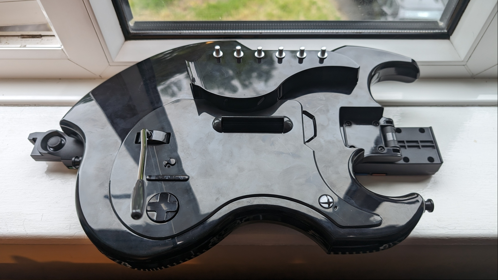 PDP Riffmaster Guitar Controller review image showing the controller folded over on a window sill.